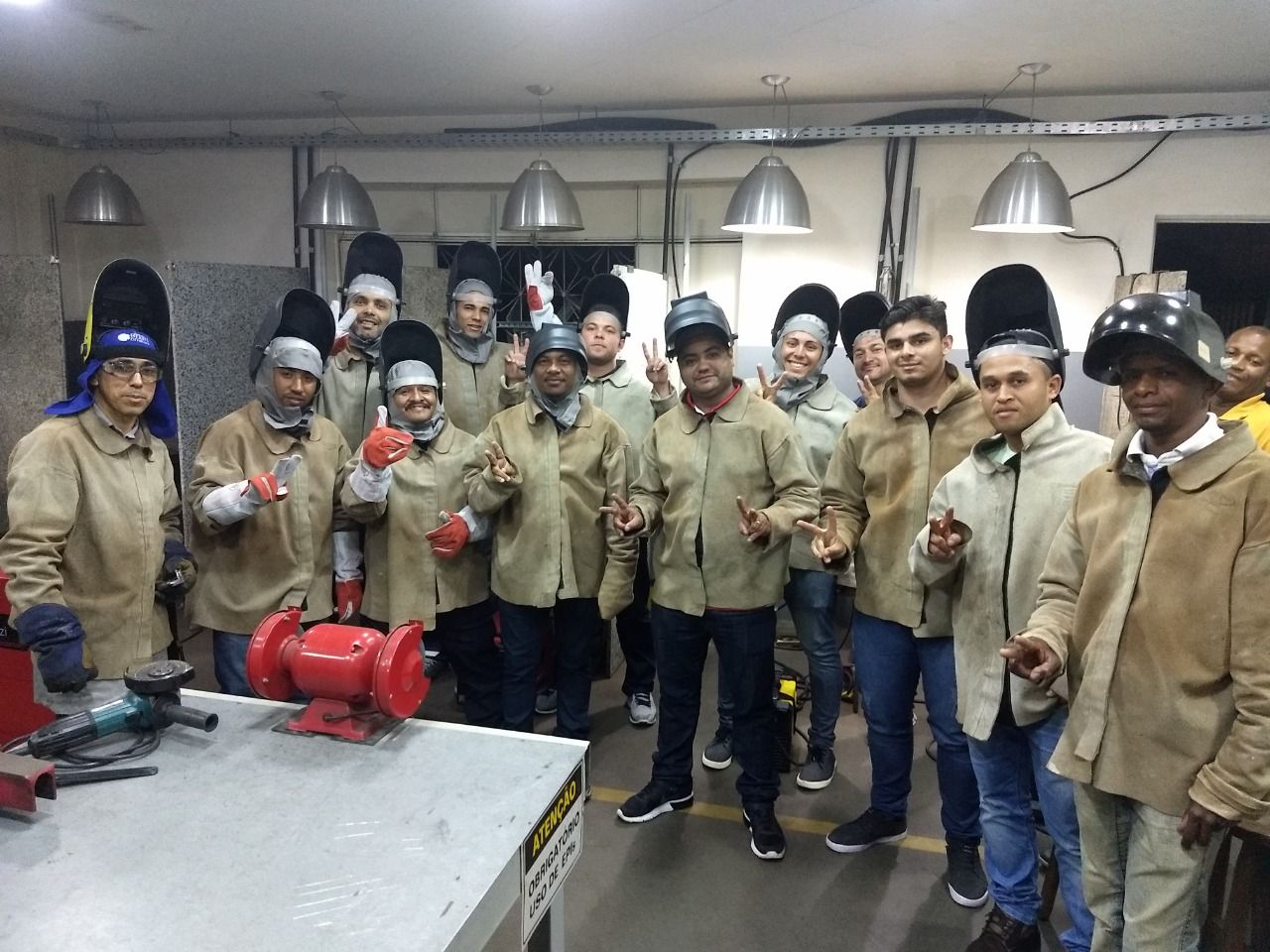 Um grupo de homens está posando para uma foto em uma oficina.